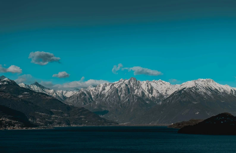 a large body of water with mountains in the background, by Julia Pishtar, pexels contest winner, visual art, boka, snow capped mountains, orazio gentileschi style, blue