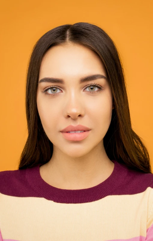 a beautiful young woman posing in front of an orange background, a character portrait, trending on pexels, photorealism, square nose, professional closeup photo, large eyebrows, ready to model