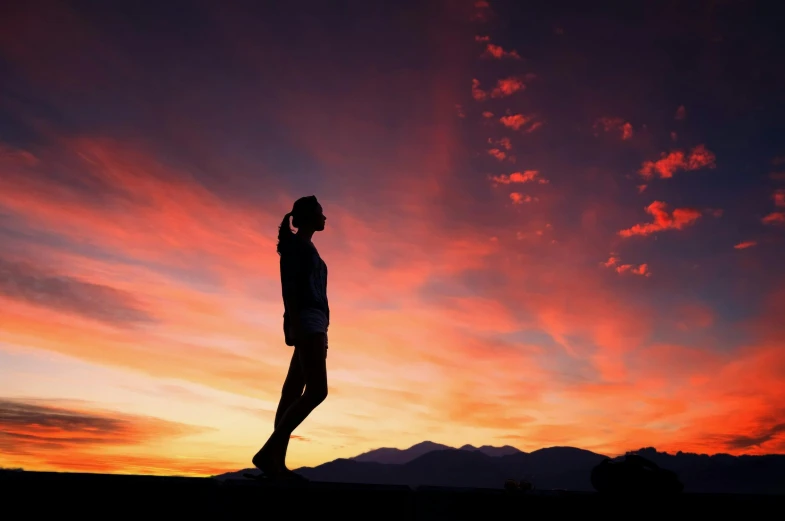 a person standing on top of a hill at sunset, by Lee Loughridge, pexels contest winner, photo of slim girl, full body profile, colorfull sky, running