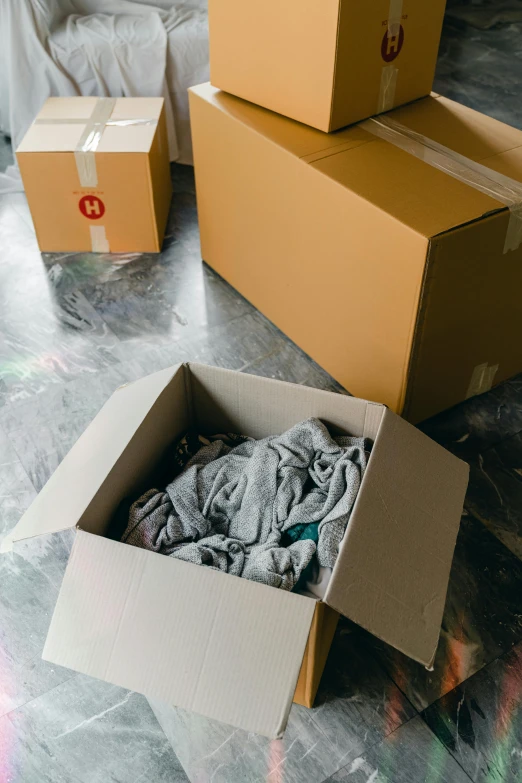 a pile of boxes sitting on top of a floor, brown clothes, thumbnail, grey, opening