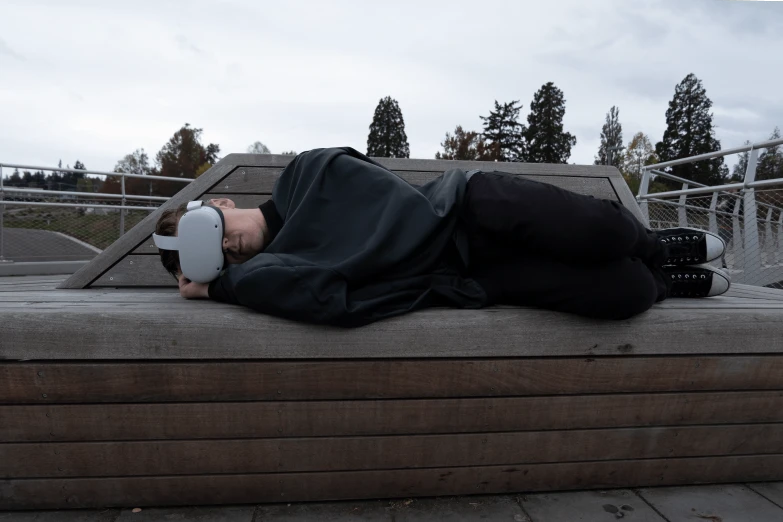 a man laying on top of a wooden bench, a hyperrealistic painting, inspired by Gustaf Munch-Petersen, unsplash, realism, wearing a vr-headset, future inflatable jacket, stock photo, vantablack gi
