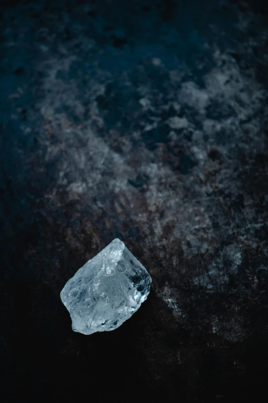 a piece of ice sitting on top of a table, unsplash, on a dark rock background, high angle close up shot, background image, ayne haag