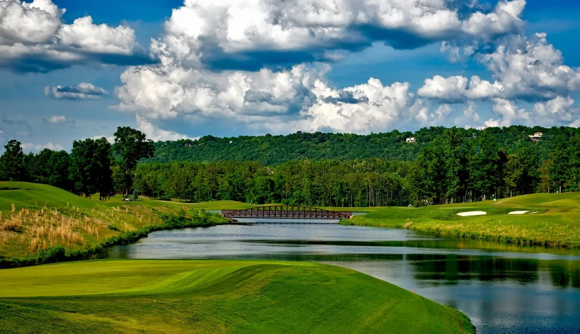 a golf course with a pond and a bridge, by Arnie Swekel, pexels contest winner, cahaba river alabama, mountainous setting, thumbnail, promo image