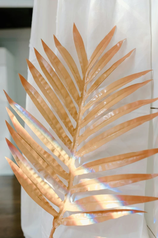 a close up of a plant in a vase on a table, an abstract sculpture, by Elizabeth Charleston, trending on pexels, kinetic art, golden and copper shining armor, palm skin, translucent pastel panels, tropical lighting