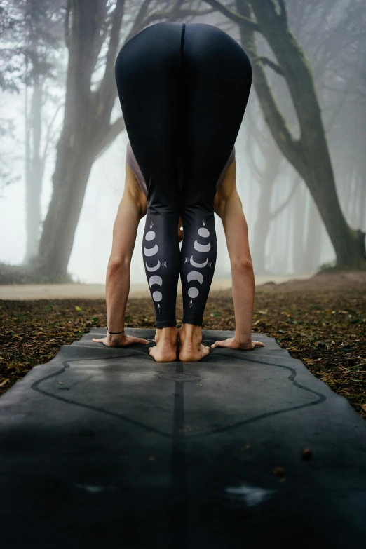 a woman is doing a handstand yoga pose, a tattoo, by Jessie Algie, pexels contest winner, an image of a moonlit forest, siamese twins, knee pads, detail shot