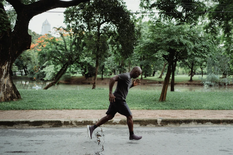 a man running on a street with trees in the background, pexels contest winner, happening, man is with black skin, profile image, vietnam, working out in the field