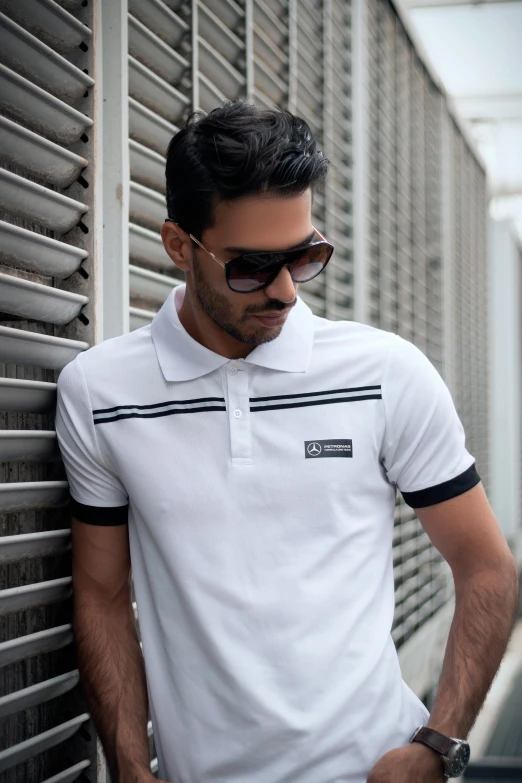 a man leaning against a wall with his hands in his pockets, a cartoon, inspired by Eugène Brands, unsplash, wearing polo shirt, white and black clothing, sri lanka, square