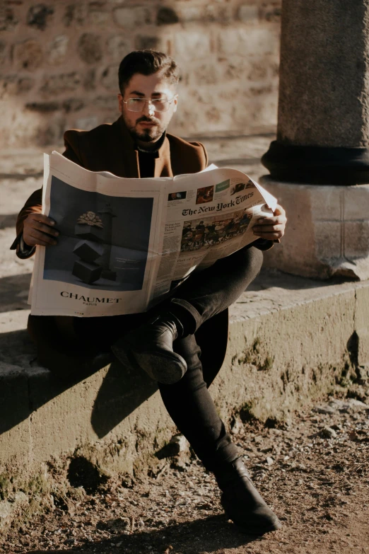 a man sitting on a ledge reading a newspaper, pexels contest winner, renaissance, trench coat and suit, singer maluma, caramel. rugged, on ground