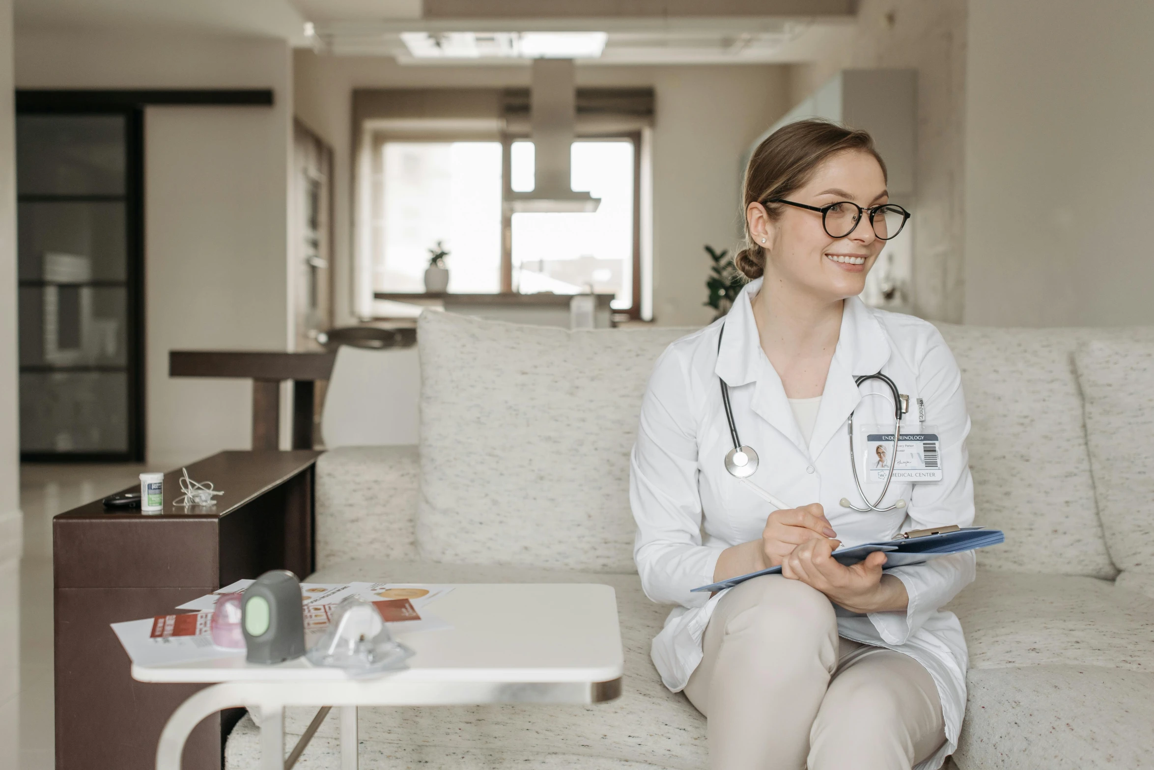 a woman with a stethoscope sitting on a couch, a picture, trending on pexels, wearing lab coat and glasses, profile image, on a table, thigh focus