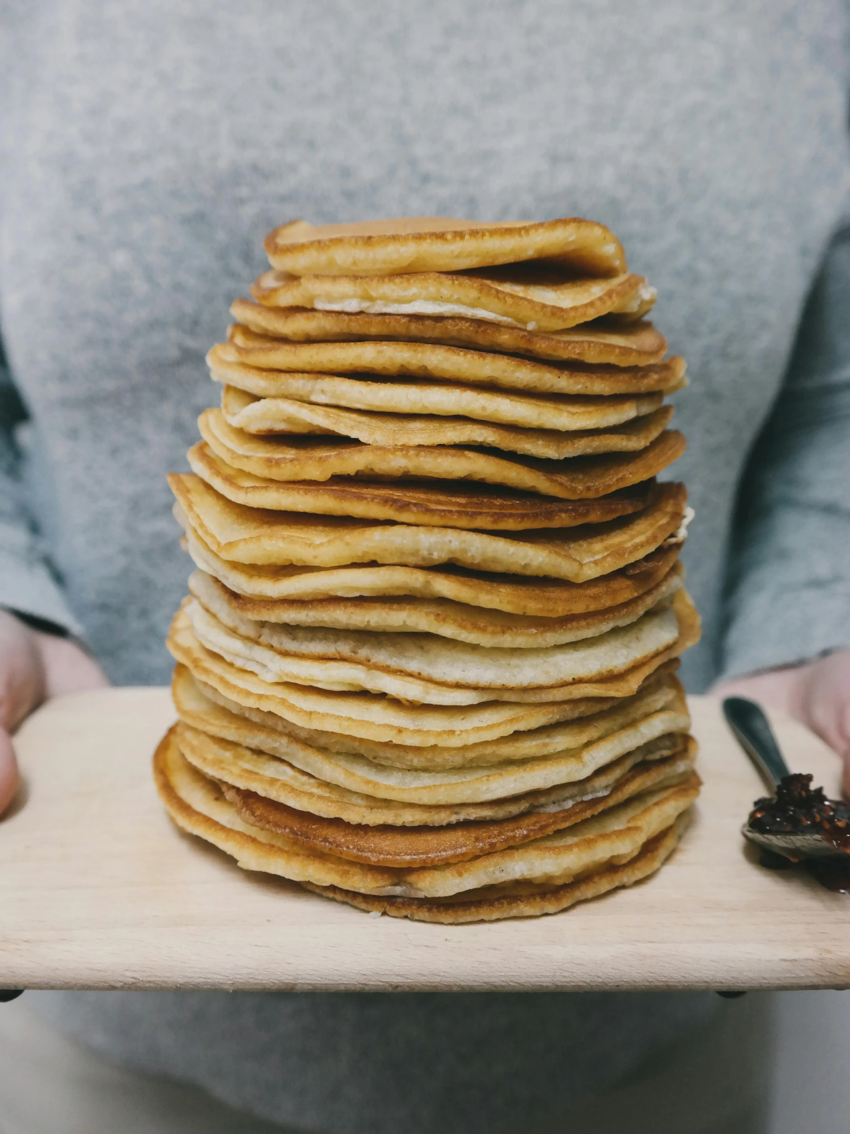 a person holding a tray with a stack of pancakes on it, by Anna Haifisch, 5k, very grainy, wood, very long