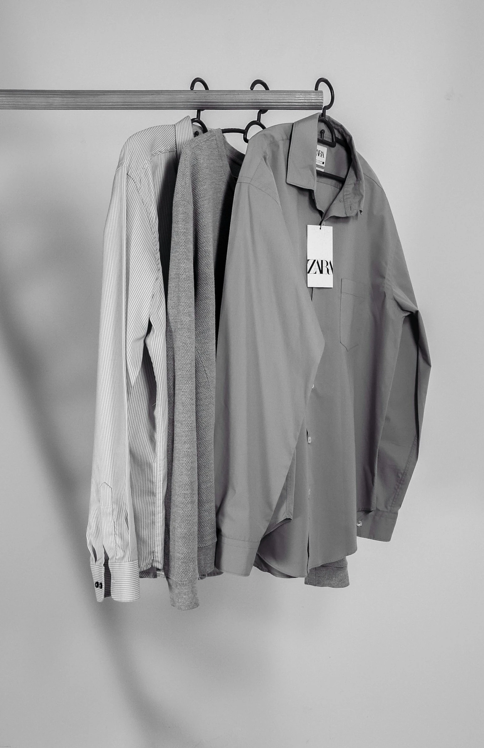 a pair of shirts hanging on a clothes rack, a black and white photo, inspired by Jan Davidsz de Hem, ( 3 1, rare ltd, lazy, may)