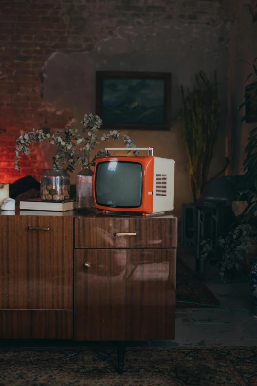 a television sitting on top of a wooden cabinet, an album cover, inspired by Elsa Bleda, trending on pexels, retrofuturism, soviet apartment, high quality photo, studio orange, cozy environment