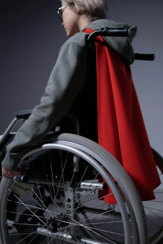 a woman in a wheelchair with a red cape, hero shot, overdetailed, superhero cape, high res photograph