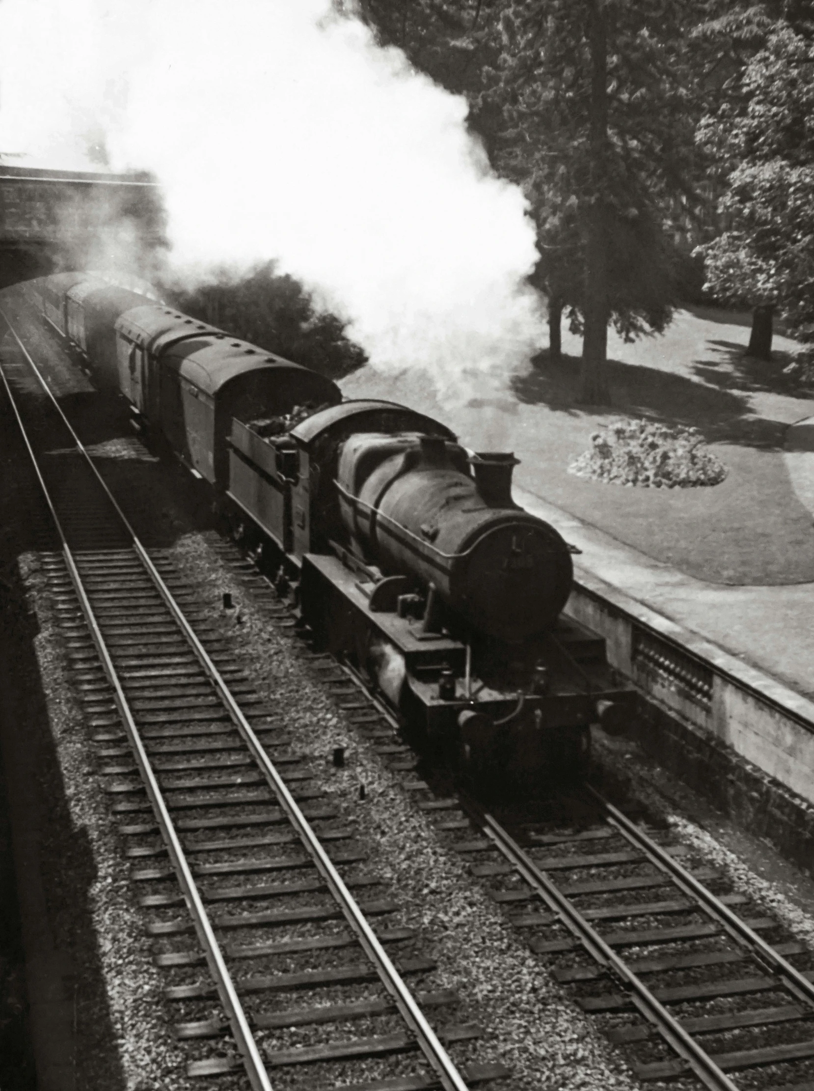 a black and white photo of a train coming down the tracks, inspired by Bert Hardy, museum photograph, 1950s photograph, al fresco, 1 9 0 0 s photograph