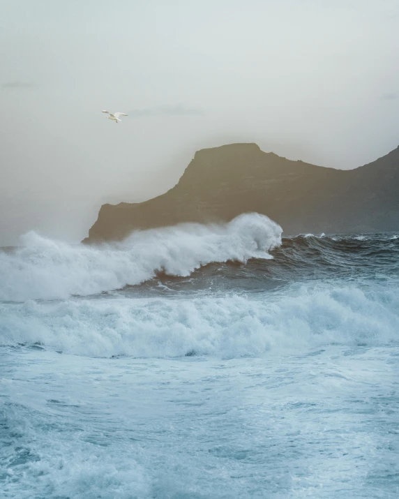 a large body of water with a bird flying over it, by Roar Kjernstad, pexels contest winner, romanticism, sea storm and big waves cliffs, today\'s featured photograph 4k, pastelwave, devil's horns