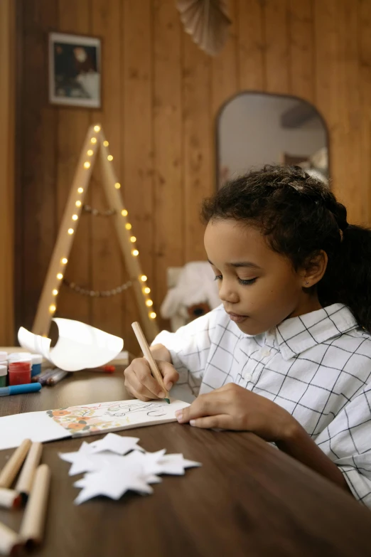 a little girl that is sitting at a table, a child's drawing, pexels contest winner, process art, holiday, light skinned african young girl, paper craft, gif
