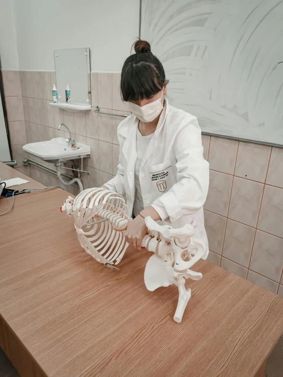 a woman in a lab coat working on a skeleton, pexels contest winner, a young asian woman, gif, at college, фото девушка курит