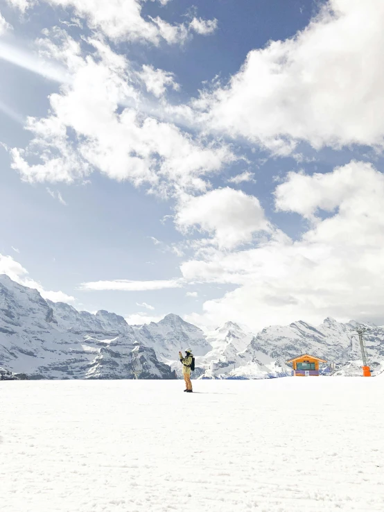 a man riding a snowboard down the side of a snow covered slope, a matte painting, pexels contest winner, photo of zurich, snow capped mountains, conde nast traveler photo, helipad