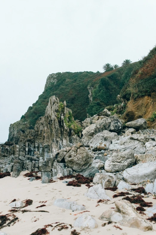 a man riding a surfboard on top of a sandy beach, inspired by Thomas Struth, unsplash, baroque, overgrown stone cave, abel tasman, hillside, ((rocks))