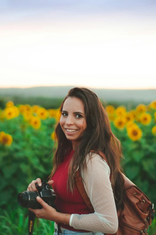 a woman holding a camera in a field of sunflowers, by Julia Pishtar, headshot profile picture, brown haired, half - length photo, avatar image