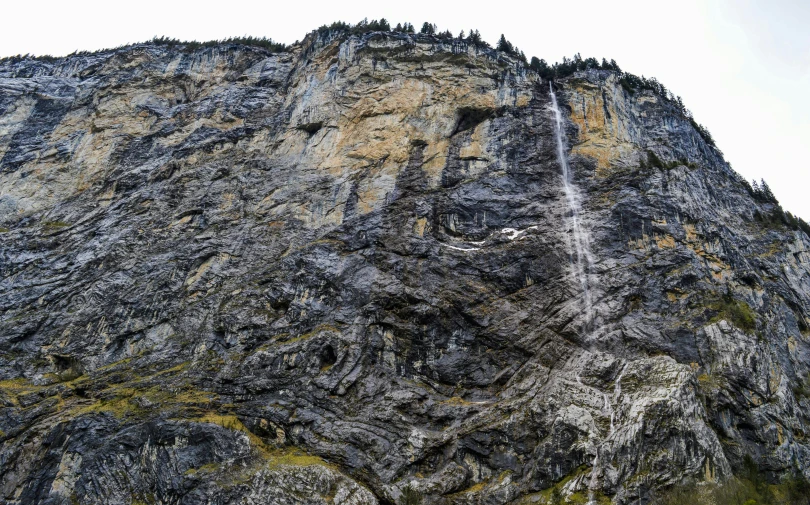 a waterfall is flowing down the side of a mountain, by Daniel Lieske, figuration libre, lauterbrunnen valley, panorama shot, detailed high resolution, rock wall