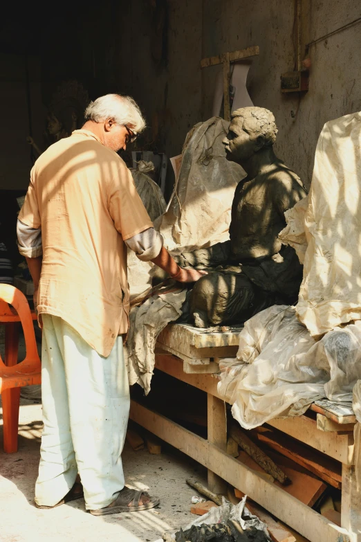 a man that is standing in front of a statue, bengal school of art, creating a soft, old man, bronze statue and silver, “ painting