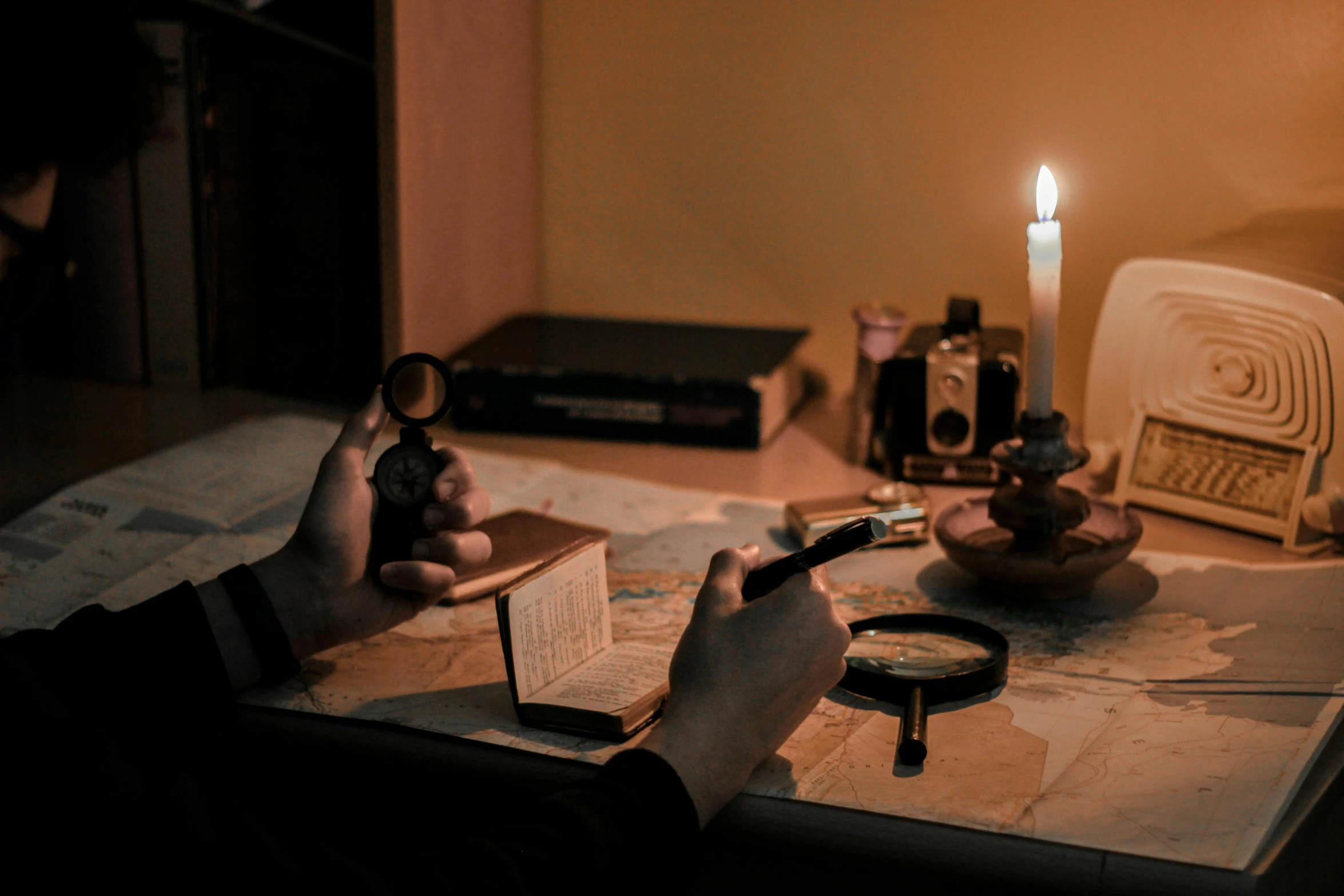 a person sitting at a table with a book and a candle, looking for clues, holding electricity, an escape room in a small, nightcap