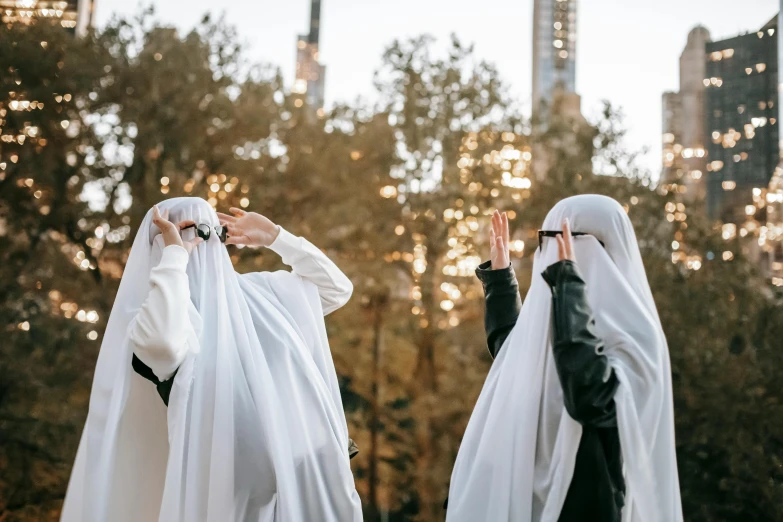 two women dressed in white standing next to each other, by Julia Pishtar, unsplash contest winner, hurufiyya, balaclava covering face, waving robe movement, ivory towers, yoko taro