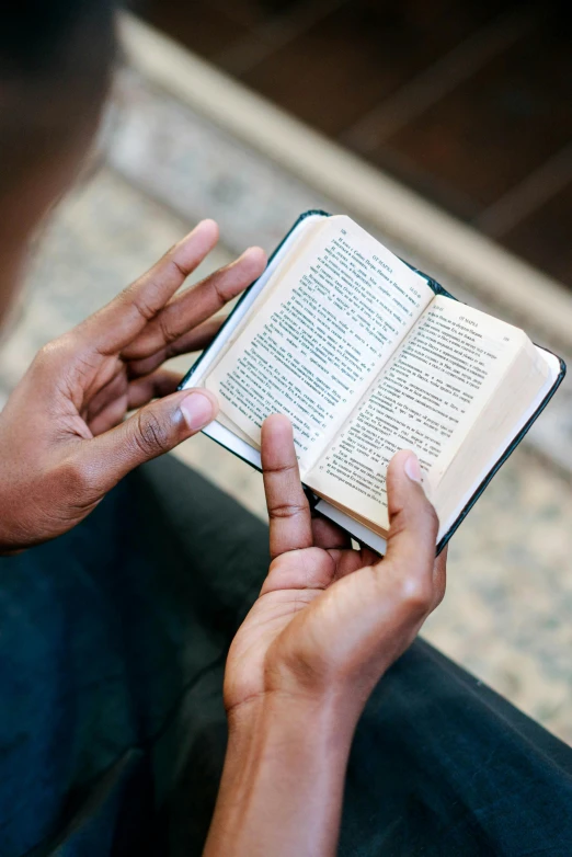 a person sitting on a couch reading a book, doing a prayer, rectangle, handheld, small in size