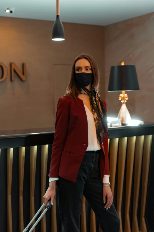 a woman wearing a face mask and holding a suitcase, by Sven Erixson, standing in a restaurant, crimson led, luxigon, wearing a blazer