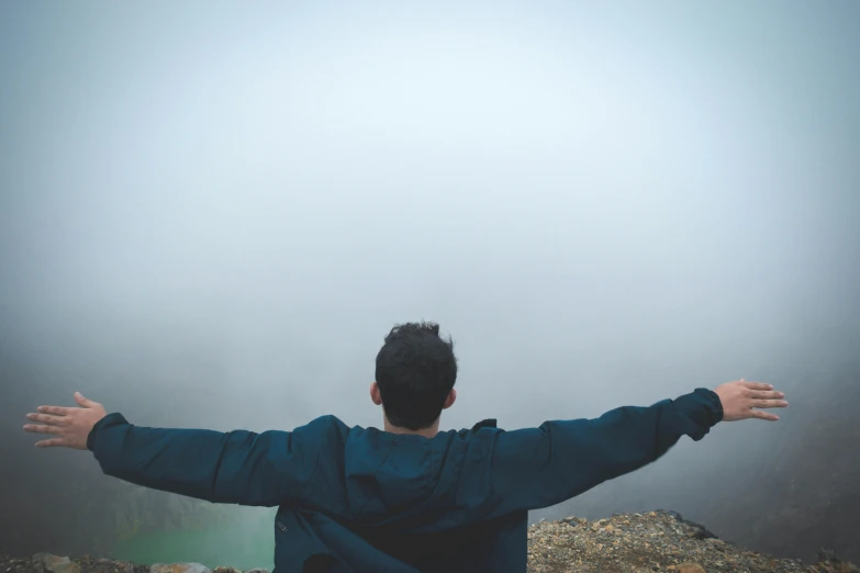 a man standing on top of a mountain with his arms outstretched, pexels contest winner, foggy day outside, sitting down casually, avatar image, open wings