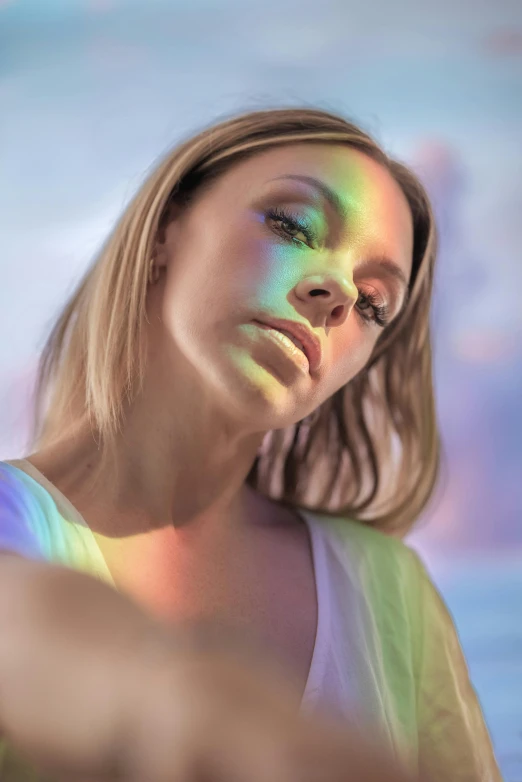a woman standing on top of a beach next to the ocean, a colorized photo, by Mark Arian, trending on pexels, holography, glowing rainbow face, portrait of nicole aniston, unreal engine : : rave makeup, sydney sweeney