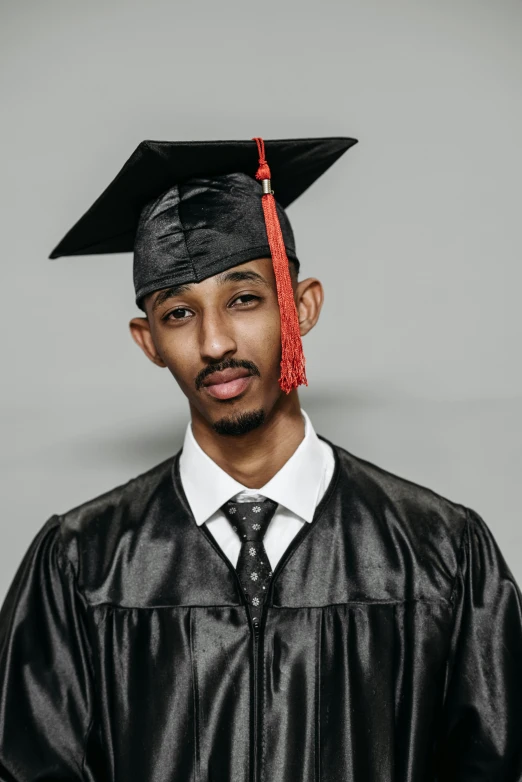 a man wearing a graduation cap and gown, riyahd cassiem, on grey background, ashteroth, getty images