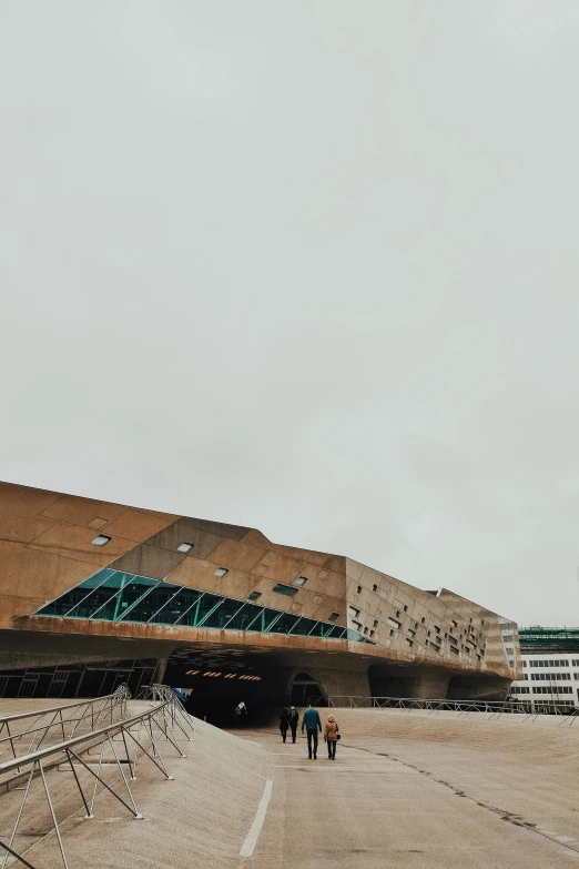 people walking in front of a building on a cloudy day, unsplash, brutalism, arena, wellington, low quality photo, brown holes