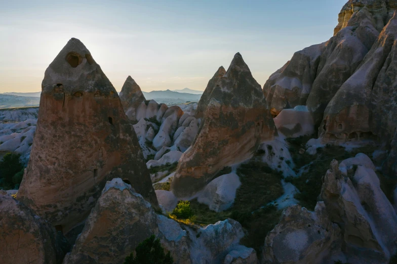 a group of rocks sitting on top of a lush green hillside, by Filip Hodas, unsplash contest winner, turkey, tall spires, victorian arcs of sand, late afternoon light