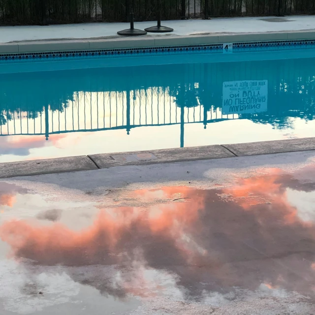 a reflection of clouds in a pool of water, a hyperrealistic painting, unsplash, stephen shore, sky is orangish outside, poolside, tie-dye