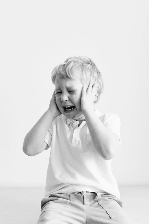 a little boy sitting on the floor covering his face with his hands, a black and white photo, pexels, screaming in pain, tinnitus, with a white background, ears are listening