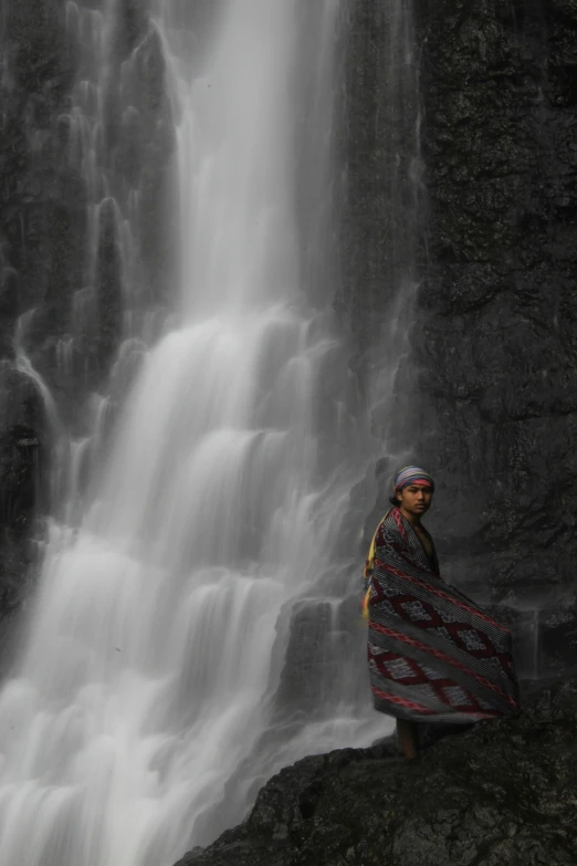 a woman standing in front of a waterfall, hurufiyya, taken in the late 2010s, wearing traditional garb, may)