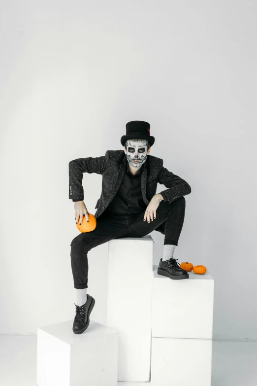 a man dressed as a skeleton sitting on top of cubes, pexels, black hat, black on white background, rex orange county, clown makeup