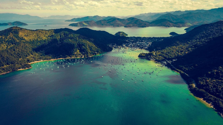 a large body of water surrounded by mountains, by Charlotte Harding, pexels contest winner, hurufiyya, abel tasman, sail boats, aerial view of a city, conde nast traveler photo