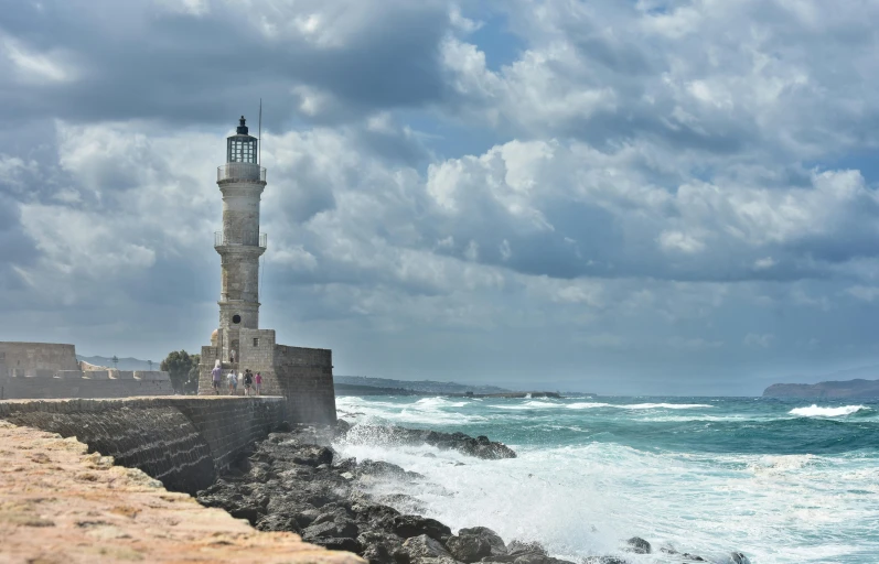 a lighthouse sitting on top of a rock next to the ocean, square, preserved historical, travel guide, rain lit