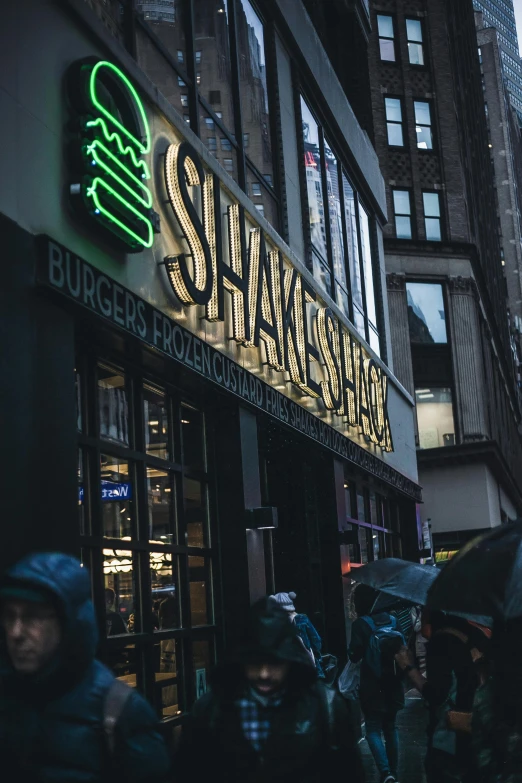 a group of people walking down a street holding umbrellas, green neon signs, shaq, shakespeare, [ theatrical ]