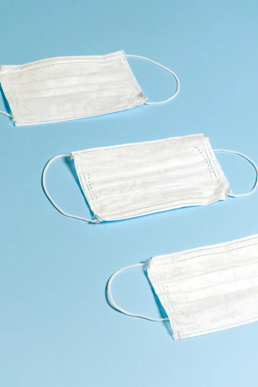 three disposable face masks on a blue background, multiple stories, thumbnail, whites, bandoliers