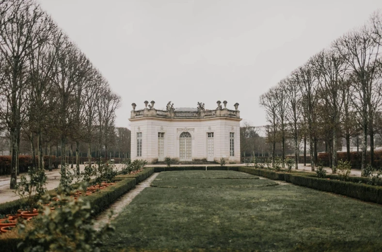 a white building sitting on top of a lush green field, a marble sculpture, pexels contest winner, rococo, against a winter garden, gloomy mood, rennes - le - chateau, mies van der rohe