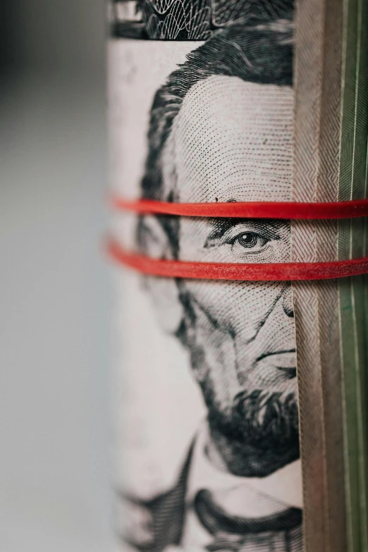 a roll of money with a picture of abraham lincoln on it, a portrait, unsplash, renaissance, red wires wrap around, ribbon, series, upclose