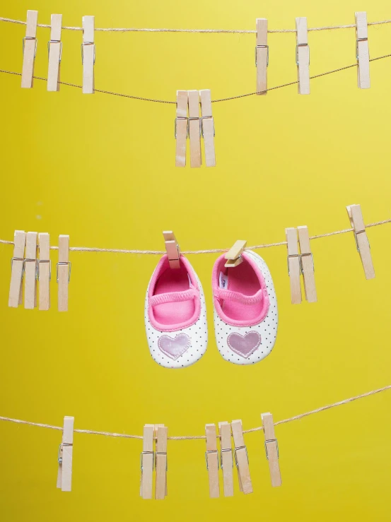 a pair of baby shoes hanging on a clothes line, inspired by Anne Geddes, pexels contest winner, yellow backdrop, panel, promo image, patterned