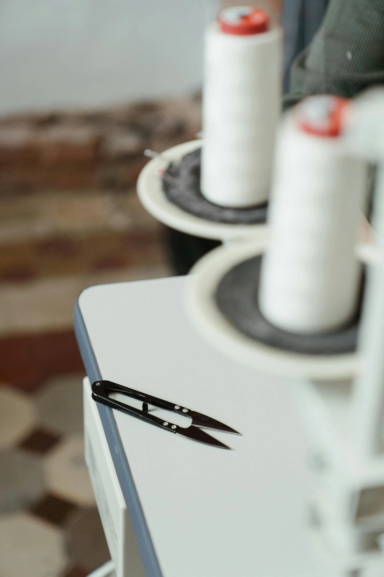 a pair of scissors sitting on top of a table, threads, detailed product image, detail shot, on display