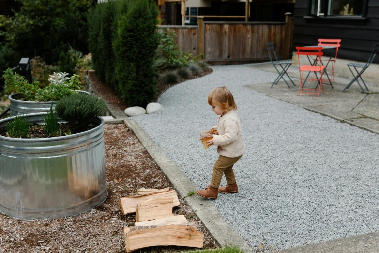 a little boy that is standing in the dirt, plants and patio, wooden logs, walking to the right, ash thorp