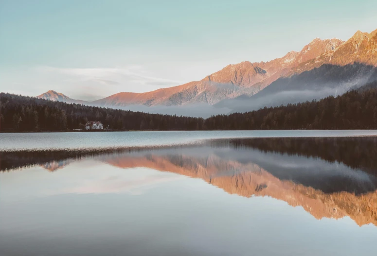 a large body of water with mountains in the background, a picture, by Sebastian Spreng, pexels contest winner, reflections in copper, muted colours 8 k, fresh from the printer, lake house
