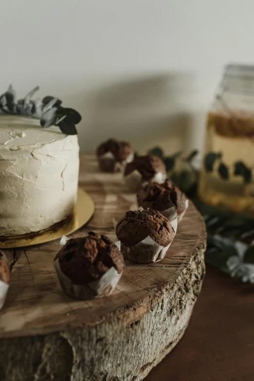 a cake sitting on top of a wooden cutting board, a still life, unsplash, party, browns and whites, chocolate. rugged, cupcake